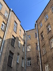 Typical urban courtyard surrounded by old residential buildings with weathered yellow-brown facades...