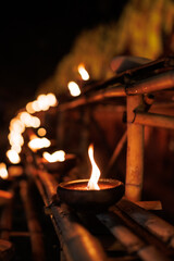 clay candle lamp burning with bright flame on bamboo rail at night during a traditional Lanna...
