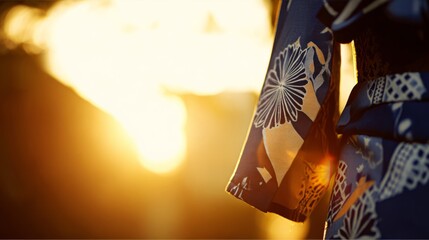 A detailed kimono sleeve with traditional dance patterns, set against a softly blurred golden sunset.
