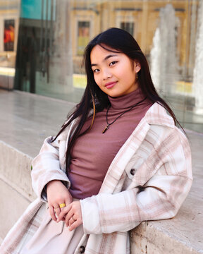 Young woman in casual outfit by urban fountain