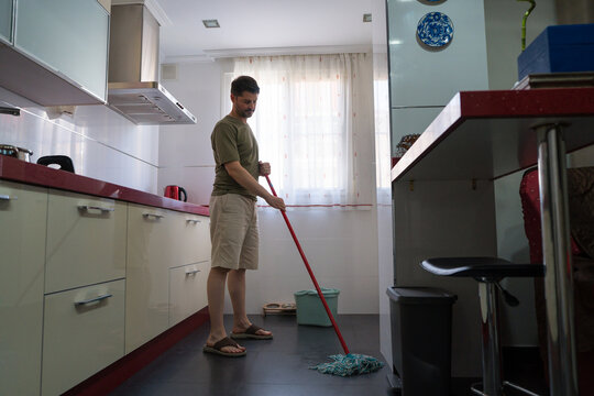 Man mopping kitchen floor in modern home setting
