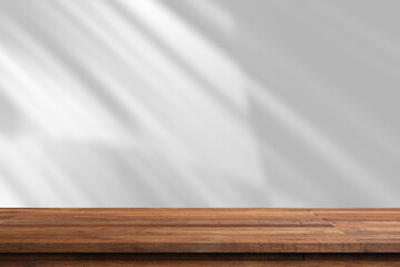 A wooden tabletop with a white wall and sunlight shining through the window.