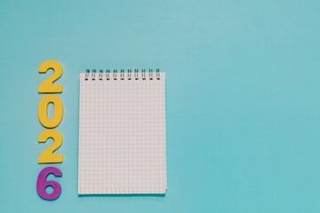 Yellow and purple 2026 next to a blank grid notepad on vibrant blue. Ideal for New Year planning, goal setting, resolutions, and 2026 events.