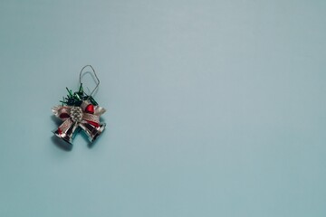 Silver jingle bells with red and green ribbons at the bottom left on light blue. Perfect for themes of holiday cheer and celebration.