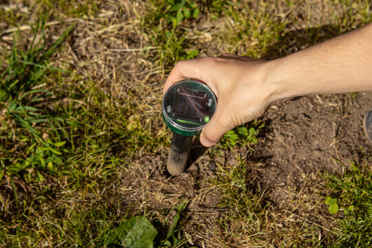 Man installs a rodent repeller in the ground. Protection of the garden from mice, moles and snakes. Solar battery