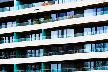 Obraz premium Modern Multi-Story Residential Building with Vibrant Facade, Large Balconies, and Scenic Urban Skyline under Clear Blue Sky