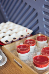 A tray of panna cotta desserts topped with raspberry sauce, ready for a event.