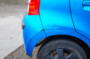 Scratches on side of blue car vehicle showing damage and paint abrasion on metal door surface...