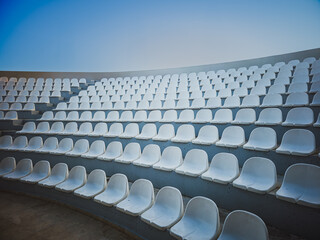 Minimalist view of empty white seats in modern open-air amphitheater