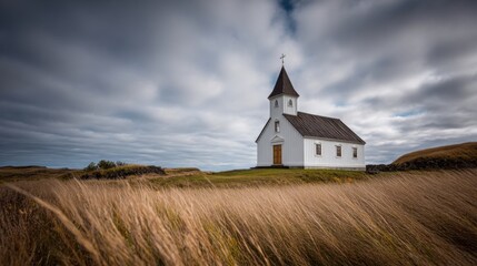 Fototapeta premium Serene White Church with Steeple on Hilltop under Dramatic Cloudy Sky in Nature.