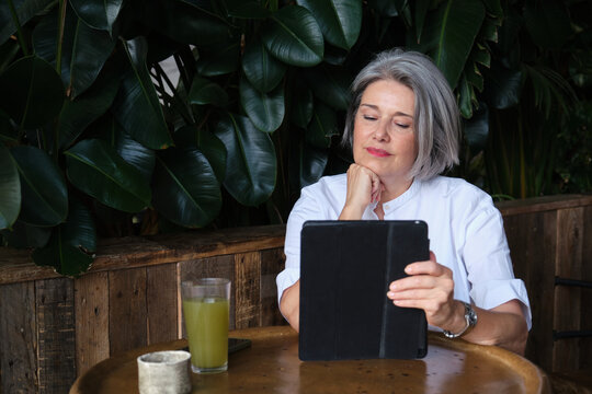 Mature woman reading tablet at a cozy cafe