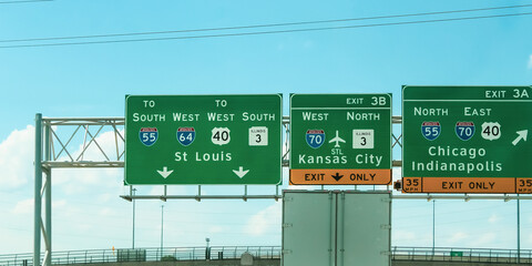 A series of green highway signs directing traffic on US interstates. I-55, I-64, and I-70. St. Louis, Kansas City, Chicago, and Indianapolis. Journey, logistics, shipping, and travel background banner