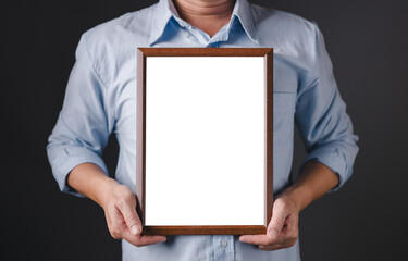 A person in a light blue shirt is holding a vertical wooden frame with a blank white space in the center, offering a clean, empty canvas ideal for text, design, branding, or message display.