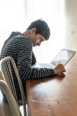 Stressed teenager with neck pain and bad posture using a laptop. Student suffering from fatigue and...