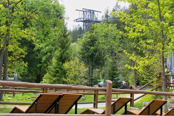 Lounge chairs sit in a landscaped park, with a distant viewing tower rising above lush trees in Zakopane - Lesser Poland - Poland