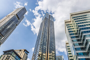Obraz premium Low angle view of ultra modern glass skyscraper soaring into blue sky with reflective facade