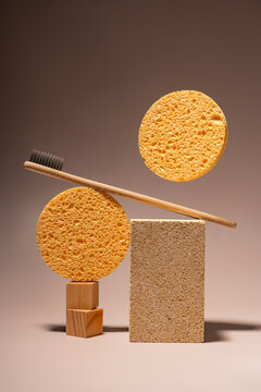 Bamboo toothbrush and sponges on minimalist brown background