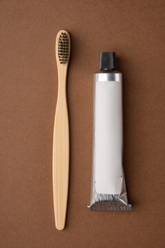 Bamboo toothbrush with tube on brown background