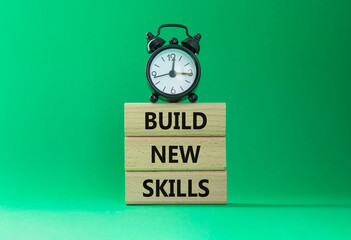 Build New skills symbol. Concept word Build New skills on wooden blocks with alarm clock. Beautiful...