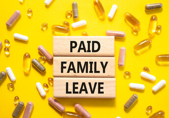 Paid Family Leave symbol. Concept words Paid Family Leave on wooden blocks. Beautiful yellow...