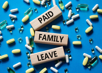 Paid Family Leave symbol. Concept words Paid Family Leave on wooden blocks. Beautiful blue...