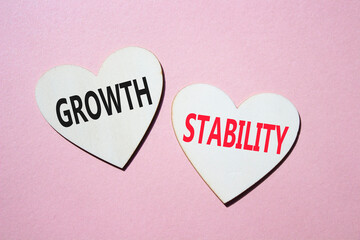 Growth and Stability symbol. Concept word Growth and Stability on wooden hearts. Beautiful pink background. Business and Growth and Stability concept. Copy space