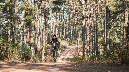 Obraz premium A couple is hiking along a forest trail on a beautiful day, enjoying nature and their outdoor adventure perfect for themes of travel, hiking, and togetherness.