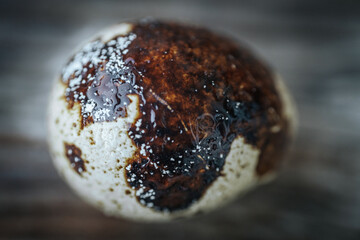 A detailed close-up of a quail egg with dark brown and white mottled patterns, placed on a rustic...