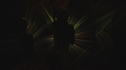 Silhouette of person surrounded by golden light streaks in darkness