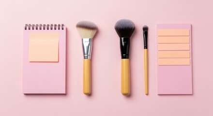 Pink notebook and makeup brushes with sticky notes on a pink background