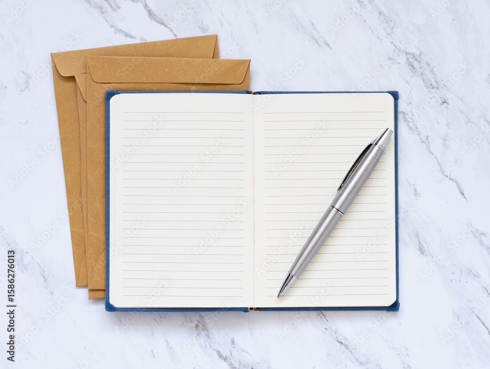Poster an open lined notebook with a silver pen rests on a marble surface with envelopes