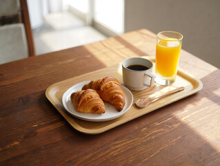 A delightful breakfast of croissants, coffee, and orange juice on a wooden tray