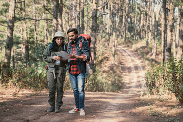 A couple is hiking along a forest trail on a beautiful day, enjoying nature and their outdoor adventure perfect for themes of travel, hiking, and togetherness.