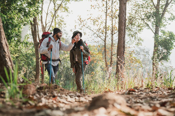 A couple is hiking along a forest trail on a beautiful day, enjoying nature and their outdoor adventure perfect for themes of travel, hiking, and togetherness.