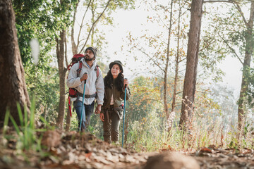 A couple is hiking along a forest trail on a beautiful day, enjoying nature and their outdoor adventure perfect for themes of travel, hiking, and togetherness. © NewSaetiew