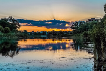 Dramatic sunset over Khorol River in Myrhorod, Poltava region, Ukraine with golden reflections on...