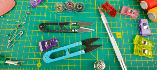 Different sewing supplies on green background, flat lay.