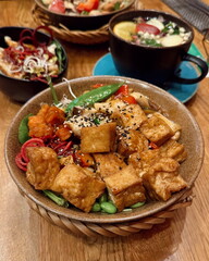 Gesunde vegane Bowls mit Tofu, Gemüse und Superfoods – serviert mit Heißgetränk