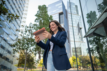 Happy businesswoman using digital tablet in modern business district