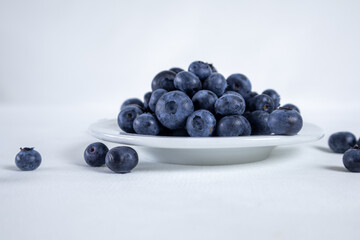 Blueberries in a white plate on a light background