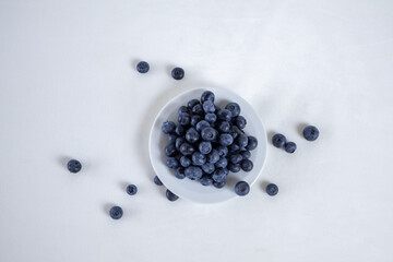 Blueberries in a white plate on a light background