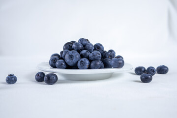 Blueberries in a white plate on a light background