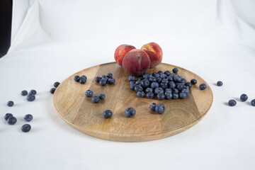 Blueberries and peaches on a wooden tray