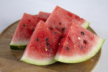Sliced watermelon on a wooden tray on a light background