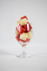 Watermelon and melon cubes in a glass on a light background