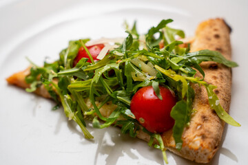 Arugula and cherry tomato pizza slice – close-up