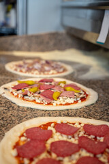 Three uncooked pizzas with toppings – kitchen prep