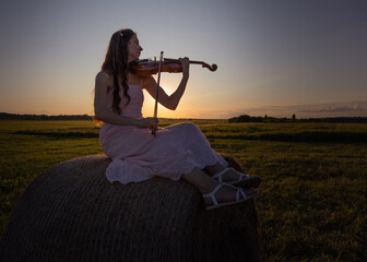 Young female with long hair violinist, plays the violin outdoors, on sundown sky background. Romantic music artist real photography © Антонина Шатревич
