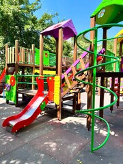 Vibrant and colorful children's playground with slides and structures, set in an outdoor park under...