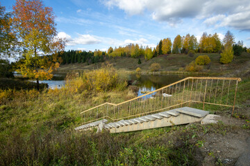 Scenic view of a winding staircase leading down to a tranquil lake surrounded by vibrant autumn...